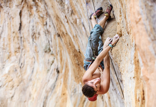 Male rock climber on a face of a cliff 