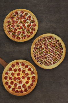 Three Pizzas On The Wooden Table, Top View