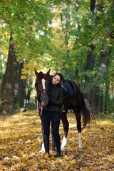 Young attractive girl with white arabian horse in the autumn forest 