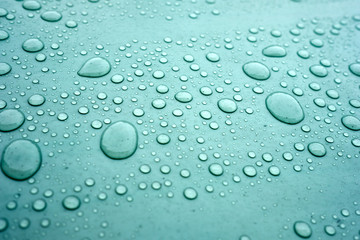 Drops of water on a dusty green color background. Shallow depth of field. Selective focus. Toned.
