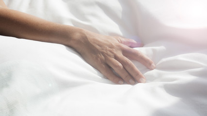 Fototapeta na wymiar closeup of female arm on white bedsheets
