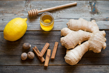 Ginger root, lemon, honey, cinnamon, nutmegs on wooden table