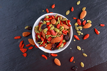 Nut mix snack with raisins, pumpkin seeds, almonds and goji berries on stone board