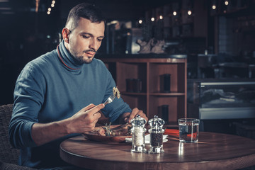 Handsome man eating tasty meat at the restaurant