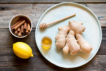 Ginger root, lemon, honey and cinnamon on wooden table