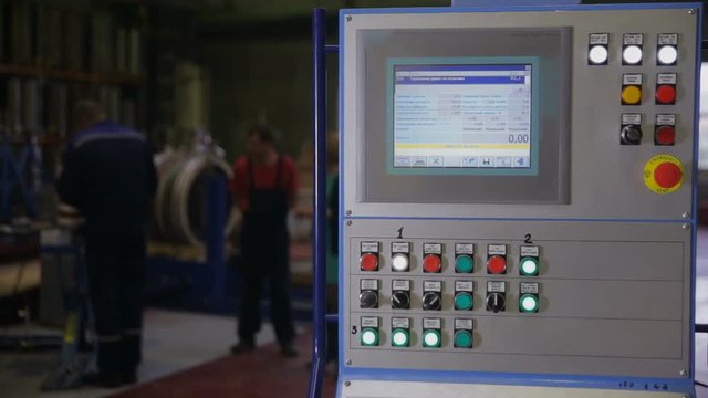 Industrial control panel, display at a modern industrial equipment. Workers operating factory machines at a background. HD.