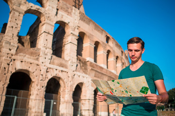 Boy with map in front of Colosseum. Young man searching the attraction background the famous area in Rome, Italy