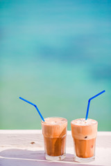 Frappe, ice coffee on the beach. Summer iced coffee frappuccino, frappe or latte in a tall glass background the sea in beach bar