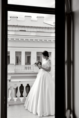 Beauty bride in bridal gown with bouquet and lace veil in the nature. Beautiful model girl in a white wedding dress. Female portrait in the park. Woman with hairstyle. Cute lady outdoors