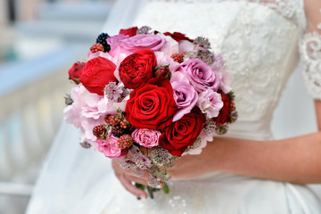 Beautiful bride is holding a wedding colorful bouquet. Beauty of colored flowers. Close-up bunch of florets. Bridal accessories. Female decoration for girl. Details for marriage and for married couple