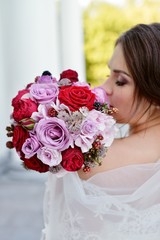 Naklejka premium Beauty bride in bridal gown with bouquet and lace veil in the nature. Beautiful model girl in a white wedding dress. Female portrait in the park. Woman with hairstyle. Cute lady outdoors