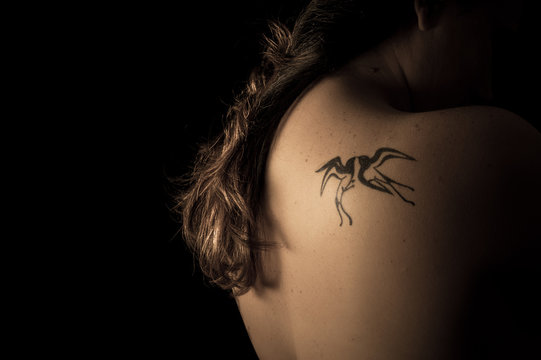 Photograph of woman's back containing a tattoo of two swallows.