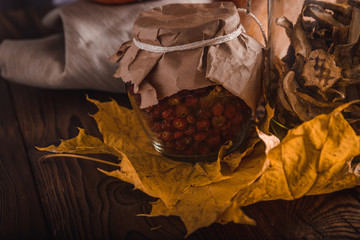 Rosehips in a glass jar on a wooden table in rustic style