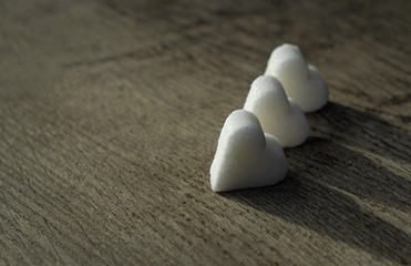 Three white sugar hearts on wooden table background