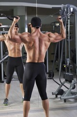 Naklejka premium Handsome powerful athletic man doing biceps exercise with cables. Strong bodybuilder with perfect muscles.