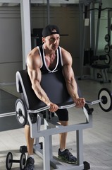 Fototapeta premium Handsome powerful athletic man doing biceps exercise with barbell. Strong bodybuilder with perfect muscles.