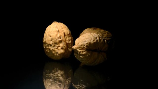 Three walnuts nuts in rotation on black background