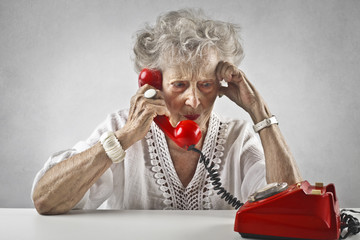 Elderly woman using a red phone