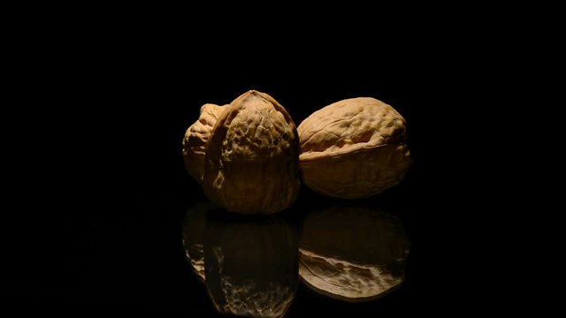 Three walnuts nuts in rotation on black background
