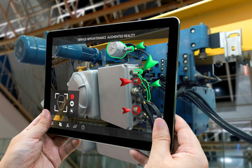 Industrial 4.0 , Augmented reality concept. Hand holding tablet with AR service , maintenance application and calling technician for check destroy part of smart machine in smart factory background - obrazy, fototapety, plakaty