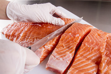 Cook cut up raw fish in kitchen