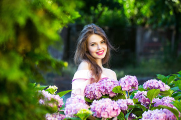 pretty smiling girl in hydrangea flowers