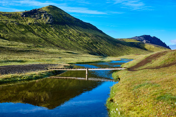 Travel to Iceland. Beautiful Icelandic landscape with bridge over creek, mountains, sky and clouds....