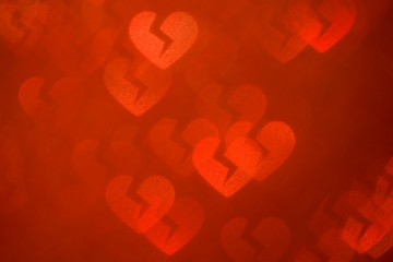 De-focused broken luminous hearts on red. Abstract red background