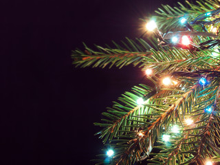 Christmas tree decked with glowing garland on a dark background