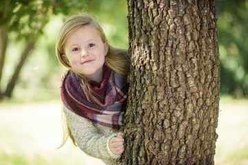 Unimaginably beautiful blond girl playing in the park hiding beh