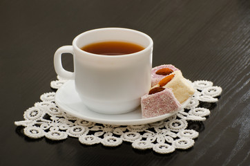 Morning cup of tea, Turkish delight in a saucer on the black desk