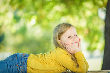 Sympathetic and beautiful little girl on a bench in a park in th © Jarek Pawlak
