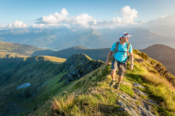 Obraz premium Mountaineer walking over a ridge in the evening light
