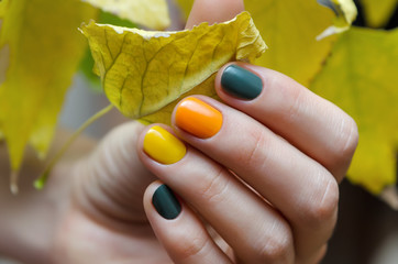 Female hand with green and yellow nail design.