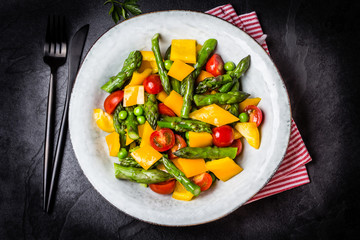 Vegetarian salad with asparagus, cherry tomatoes, bell pepper, slate background