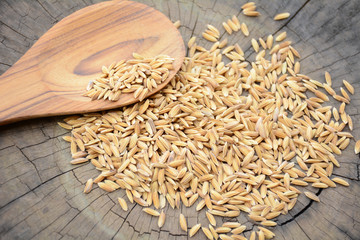 Paddy in wooden spoon.Wood background with cracks.