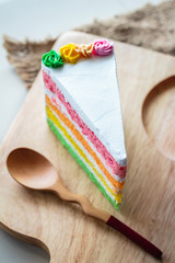 Delicious rainbow cake on wood plate.
