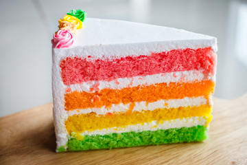 Delicious rainbow cake on wood plate.