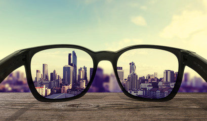 Sunglasses on wooden desk, focused on lens city view 