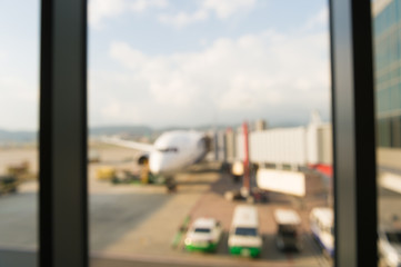 Abstract defocused bokeh of airplane at airport gate with sun coming out after the rain. Modern travel concept and wander lifestyle at sunset. Focus on raindrops with warm vintage filtered look