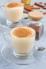 Healthy rooibos red tea latte topped with cinnamon, in glass cup and ingredients on background, vertical