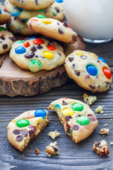 Shortbread cookies with multi-colored candy and chocolate chips on wooden board, vertical