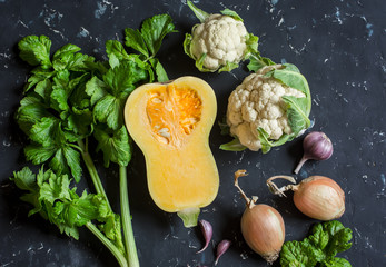 Fall vegetables on a dark background - pumpkin, cauliflower, celery, onion, garlic. Top view