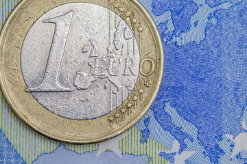 Detailed close up of an one euro coin on a twenty euro banknote