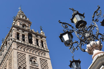 Fototapeta na wymiar Detail view of the Giralda bell tower, Cathedral of Seville, Andalusia Antique street lamppost on square near historical building.