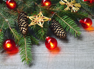 Christmas or New Year decoration with fir tree branches,red garland lights,cones and toys on old wooden background.Winter holidays,Christmas or New Year concept.Copy space,selective focus.