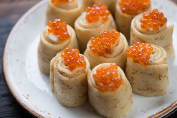Pancake rolls with salmon caviar topping, close-up