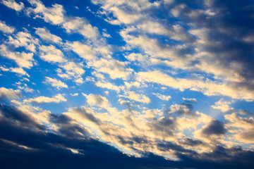 Naklejka na ściany i meble White fluffy clouds in blue sky at sunset, sky background.