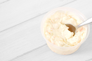 Coleslaw in a plastic tub with a spoon