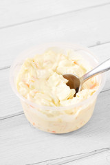 Coleslaw in a plastic tub with a spoon